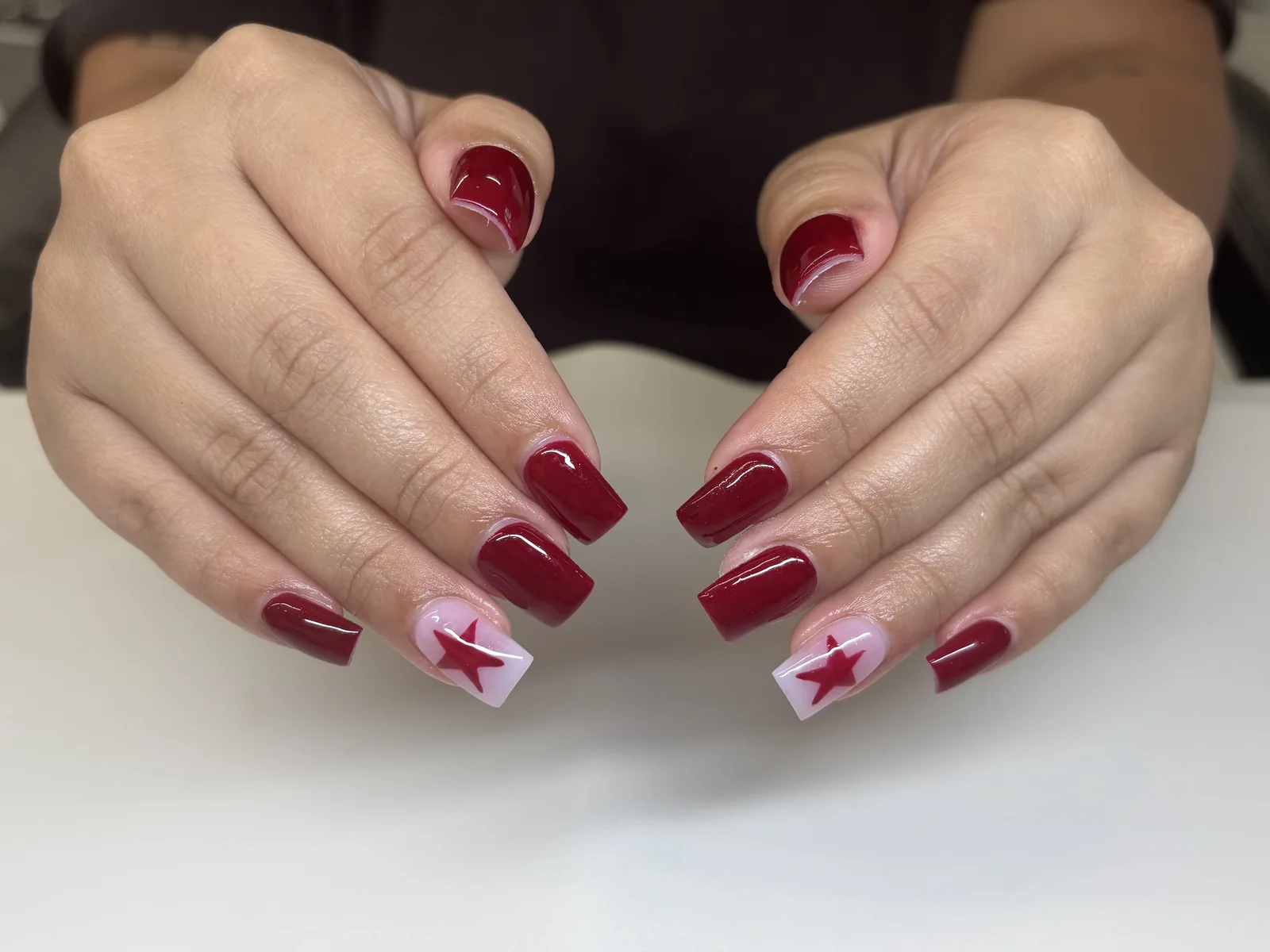 Ruby red square nails with white star details by Top Ten Nails Spa